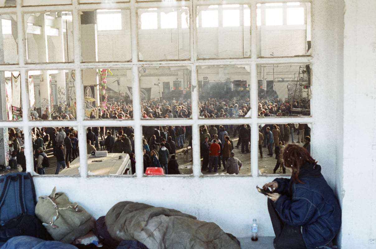 Annie-crouched-looking-through-window-at-main-room-crowd-Badalona-Spain-2000â__2001